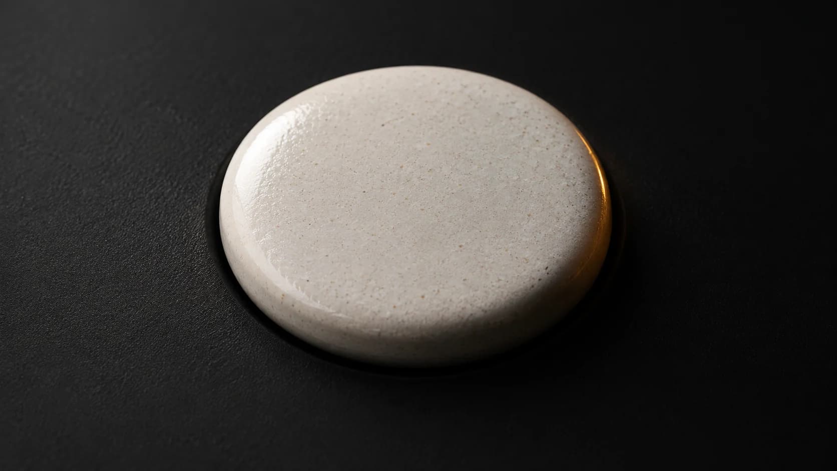 Raised ceramic tactile dot on matte black material.